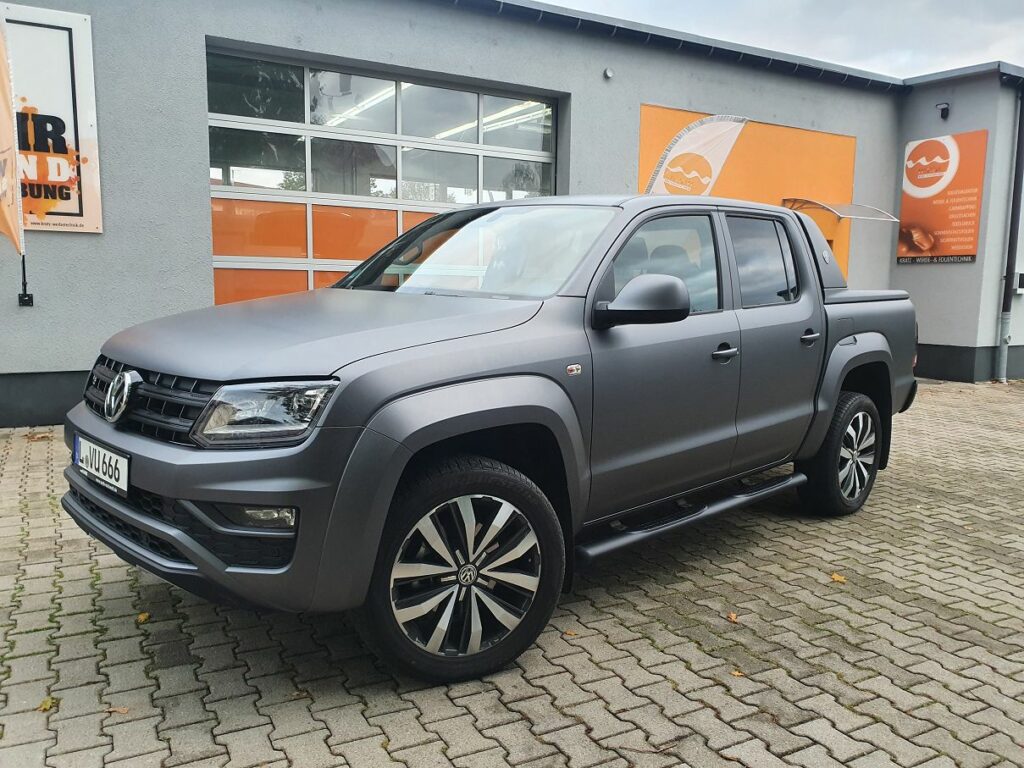 Matte grauer Volkswagen Amarok Pickup mit Lackschutzfolierung, geparkt vor dem Gebäude der Firma Kratz Werbe- & Folientechnik.