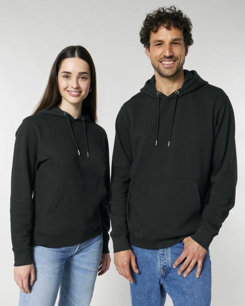Das Bild zeigt einen Mann und eine Frau. Beide tragen einen schwarzen Stanley Stella Hoddie in schwarz.